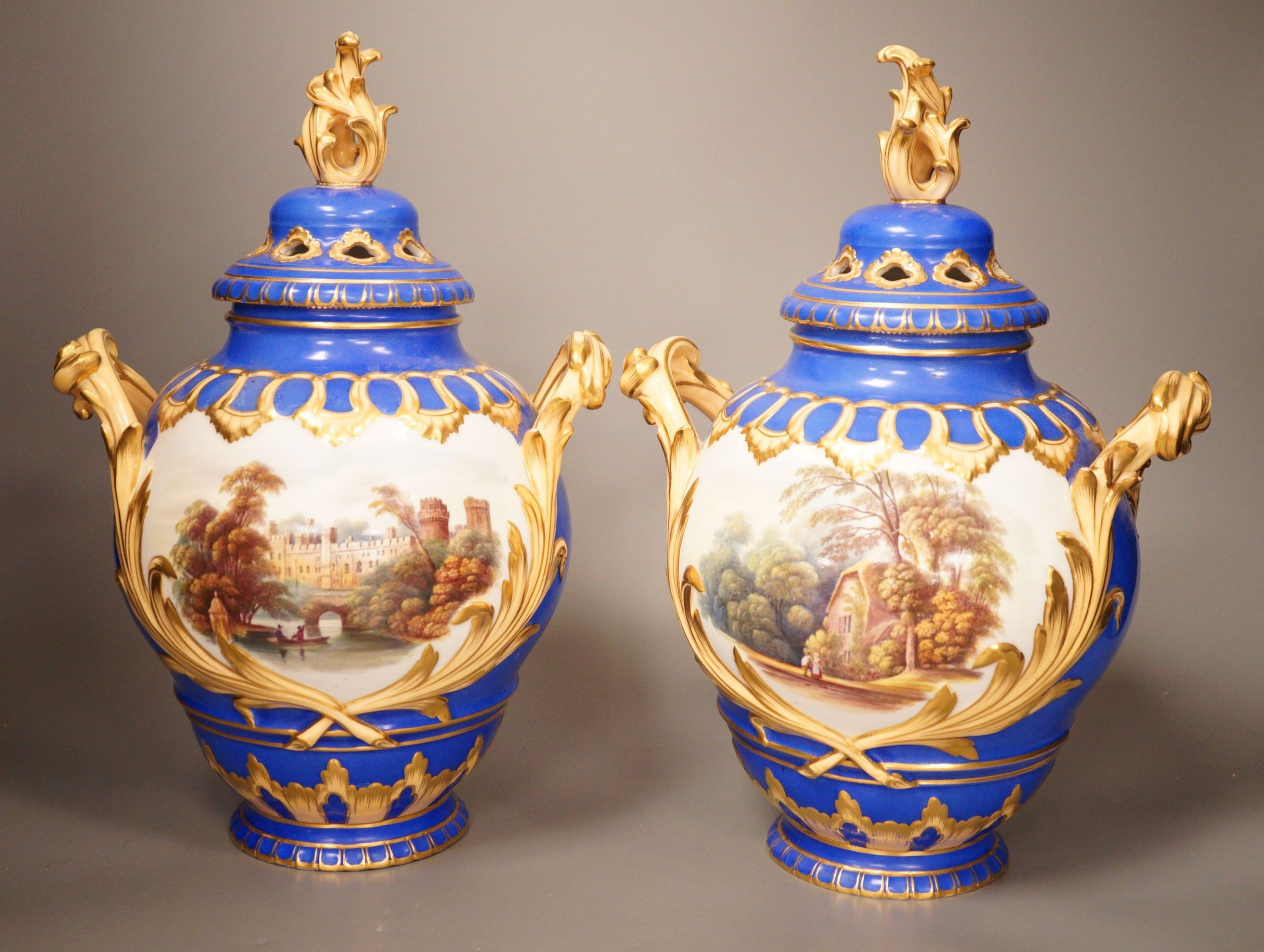 A pair of English bone China lidded two-handled vases, painted with river landscapes, within blue and gilt fields, circa 1840, 33cm